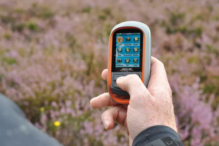 a person holding Magellan eXplorist GPS in hand