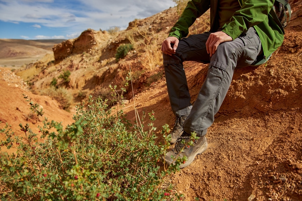 A view of a person sitting at a rock while hiking wearing hiking shoes