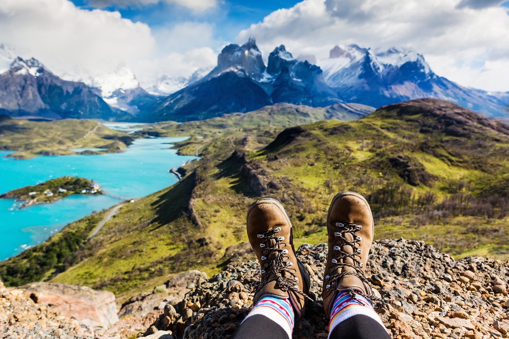 A view of a person sitting on a mountain wearing hiking boots