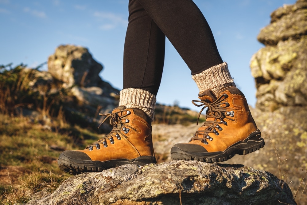 A view of a woman wearing hiking boots walking over a rocky surface