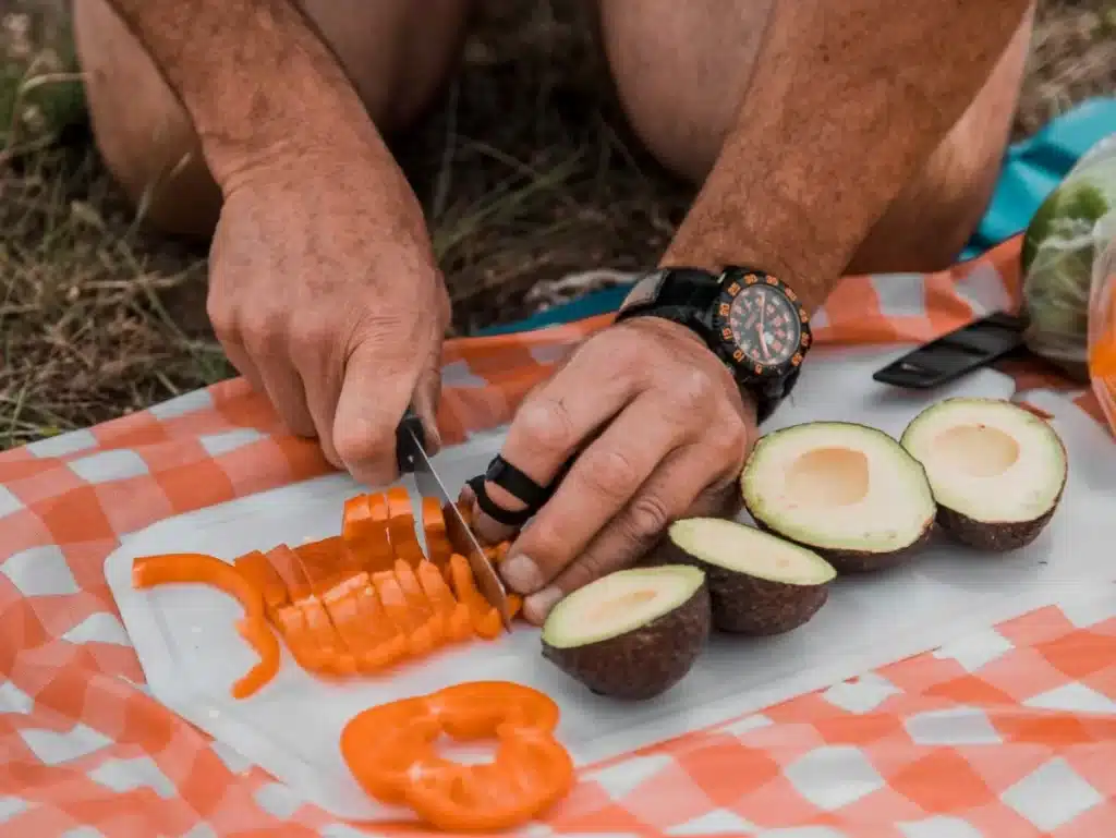 A person cutting fresh fruits at a hiking trail