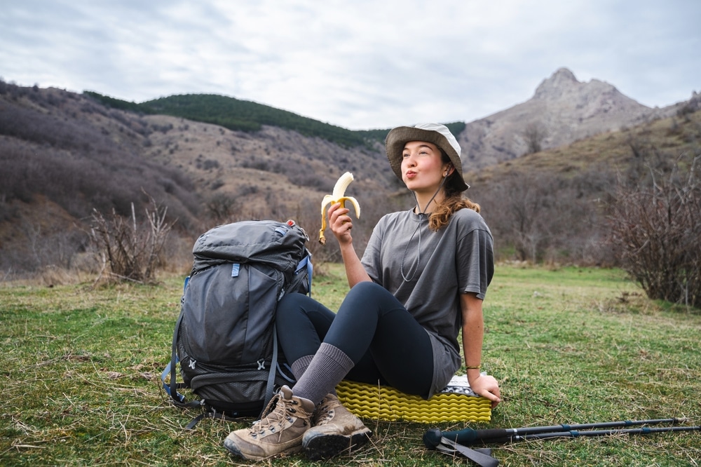 A view of a woman on a hike eating a banana