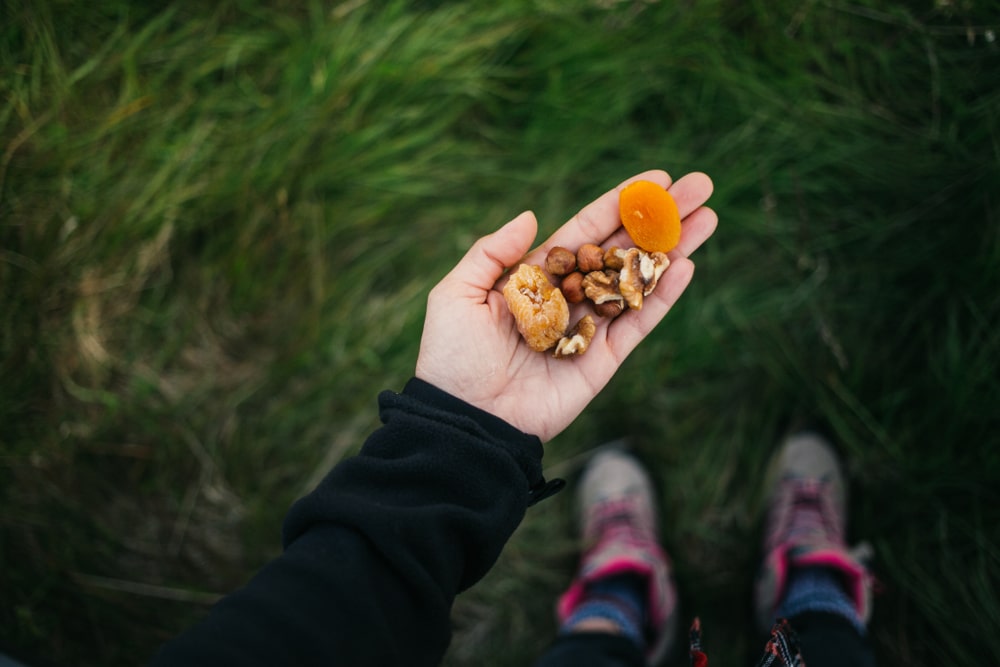 An overhead view of a hand carrying dried fruits and nuts