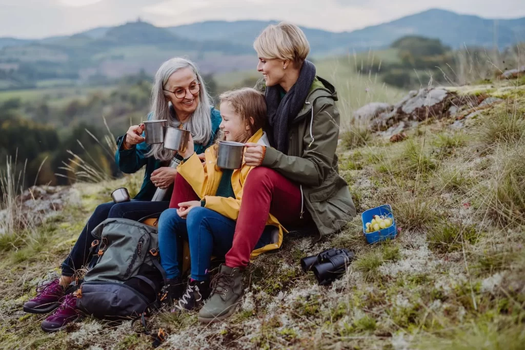 Two women with one little girl eating and drinking at a hiking trail