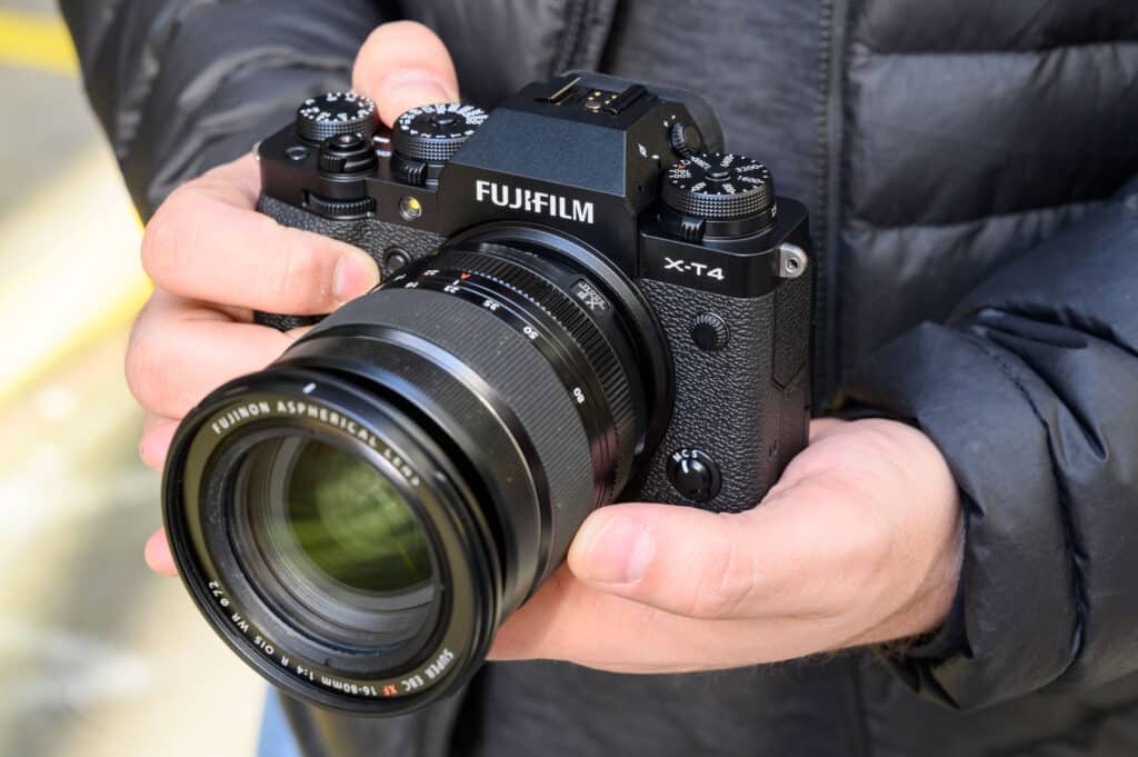 a person holding fujifilm black cam in both hands