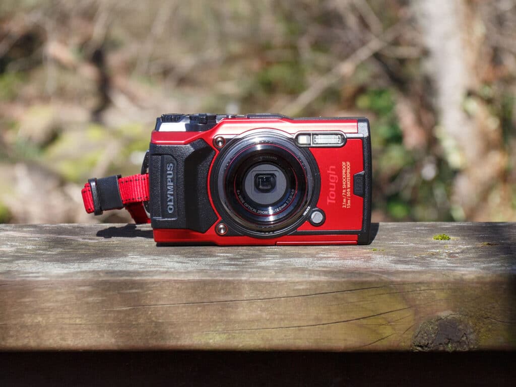 black and red olympus camera placed on wooden surface