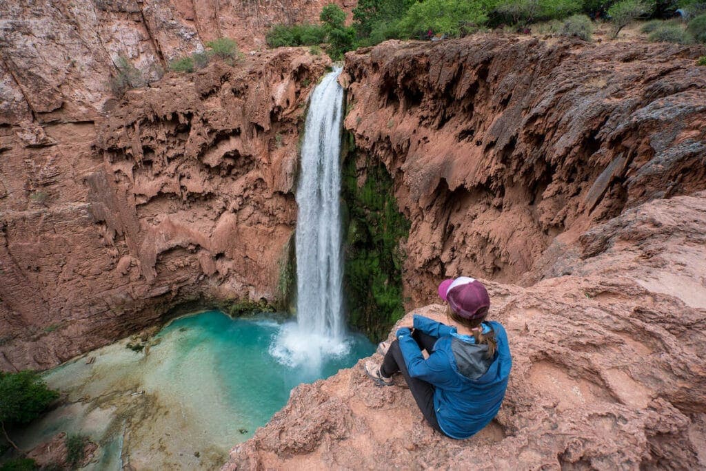 a female hiker sitting on top of havasu fall