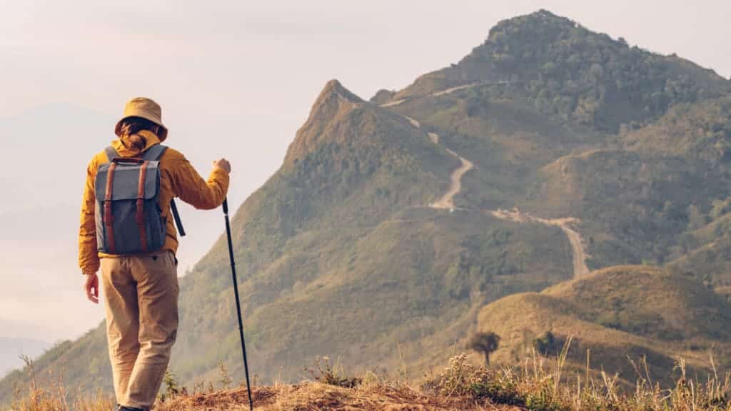 Tourist woman standing on mountain edge with beautiful mountain peak in front of her