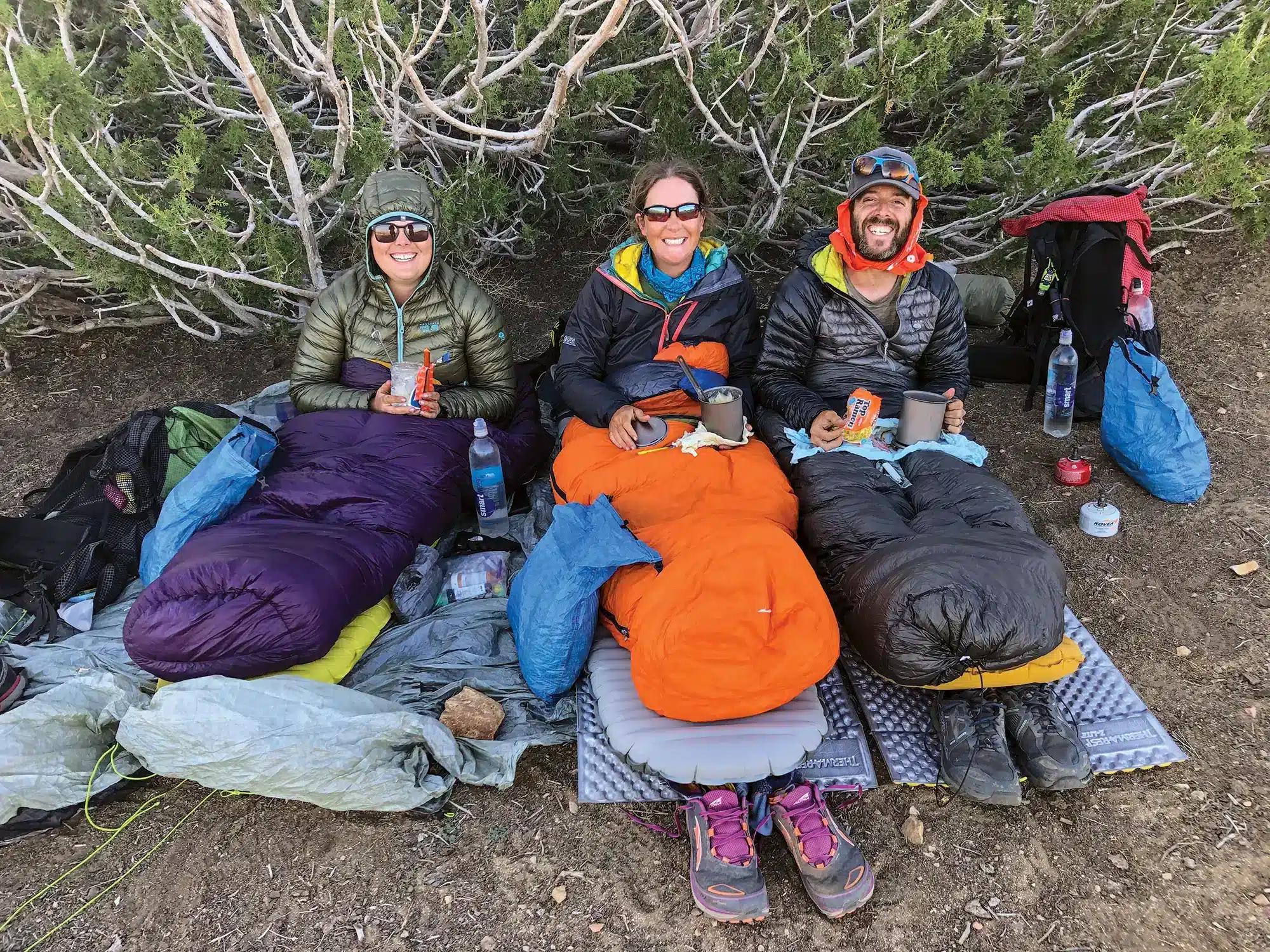 hikers posing for picture sitting on groudn with hiking gear