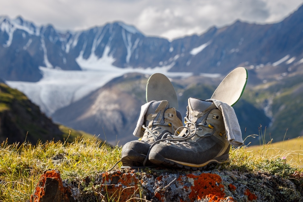 Trekking boots with insoles and socks dry on the background of a mountain valley