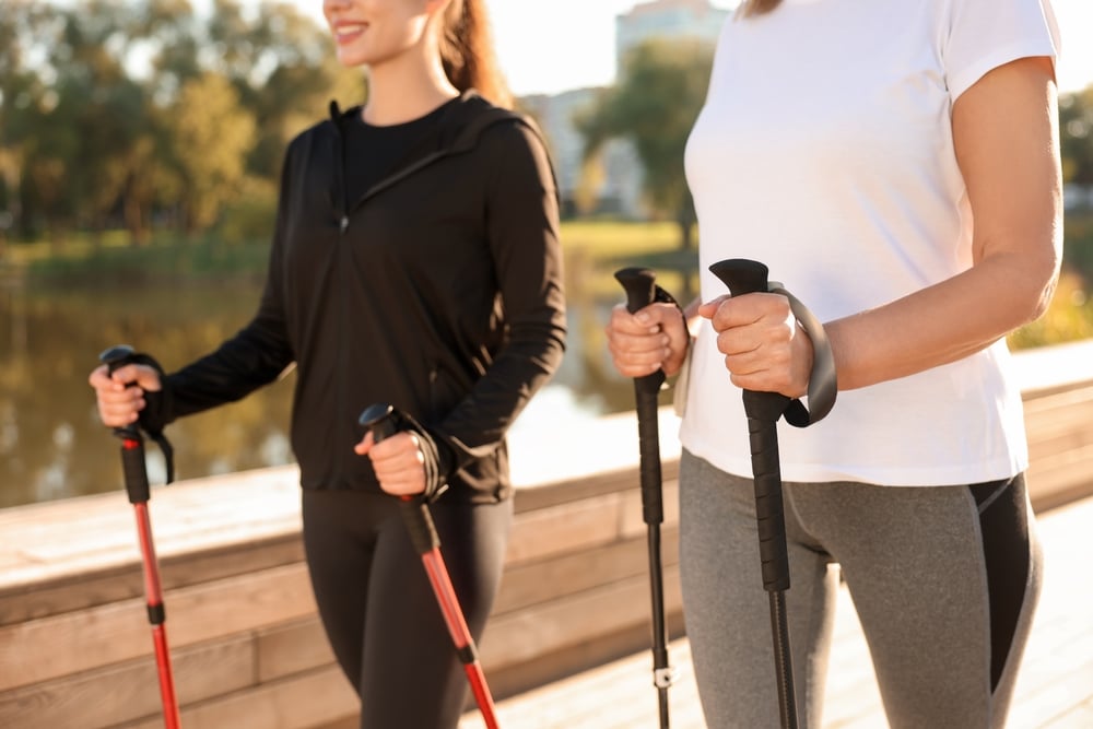 Women Practicing Nordic Walking With Poles Outdoors On Sunny Day