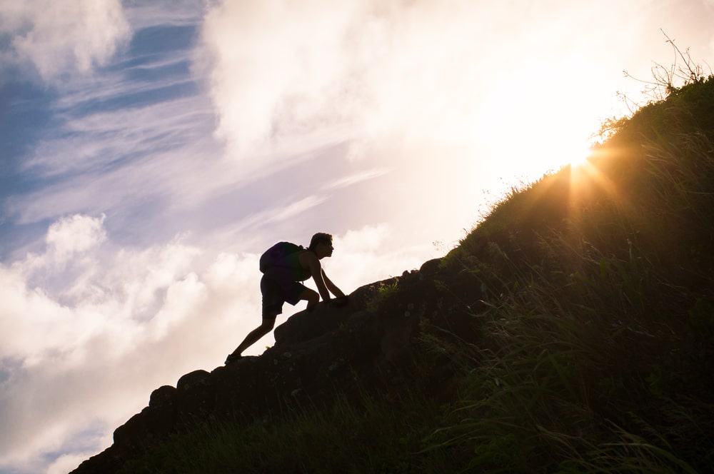 Young man climbing up a mountain. 