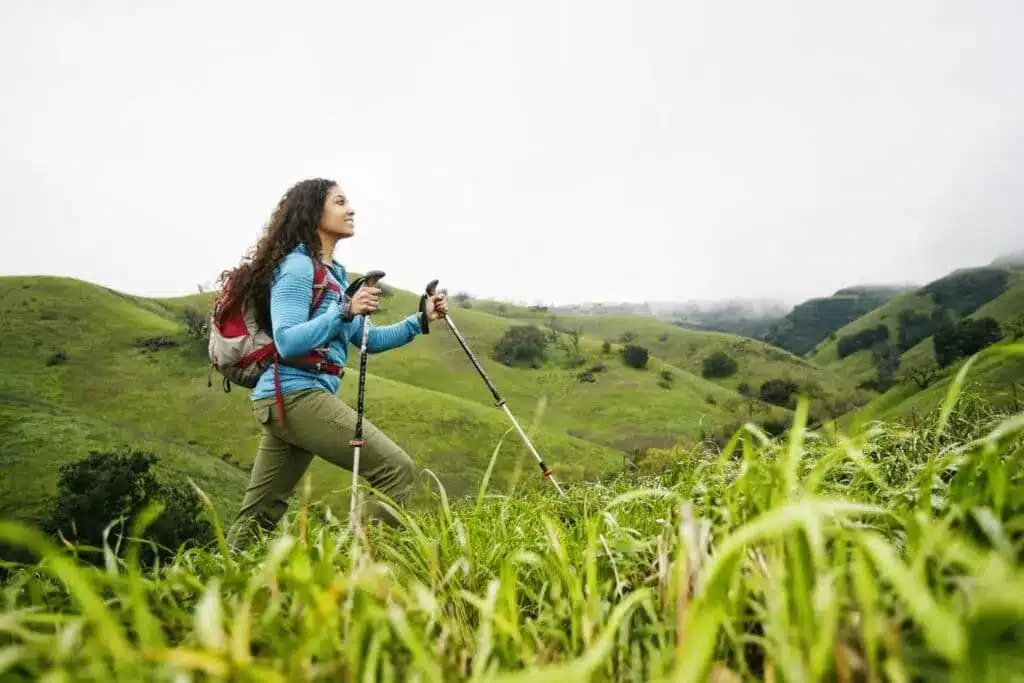 a female hiker walking in fields using poles