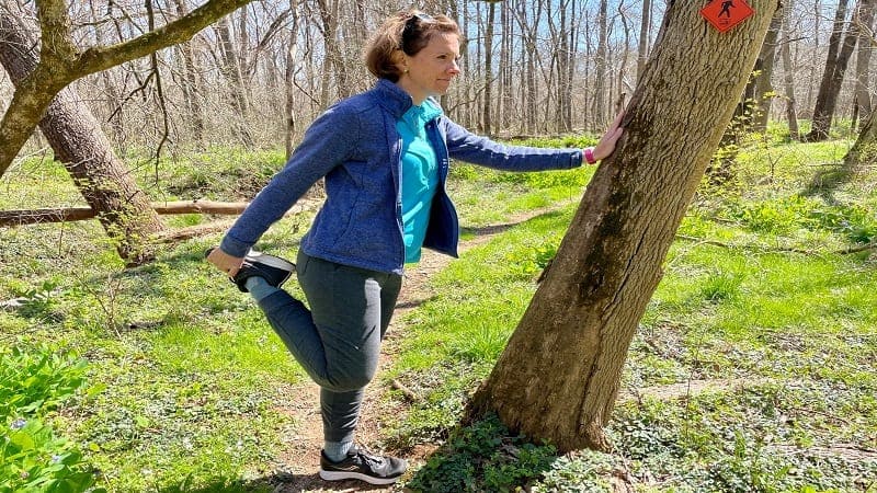 a female stretching her legs in a forest