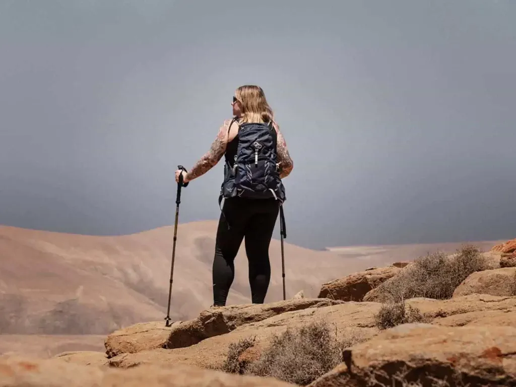 female hiker from the back holding walking sticks