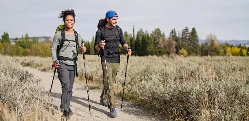 male and female hikers holding poles and walking