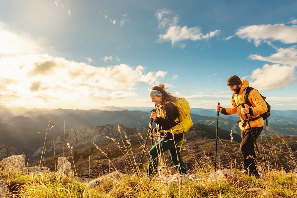 two mountaineers, male and female, trekking up a mountain at sunset.