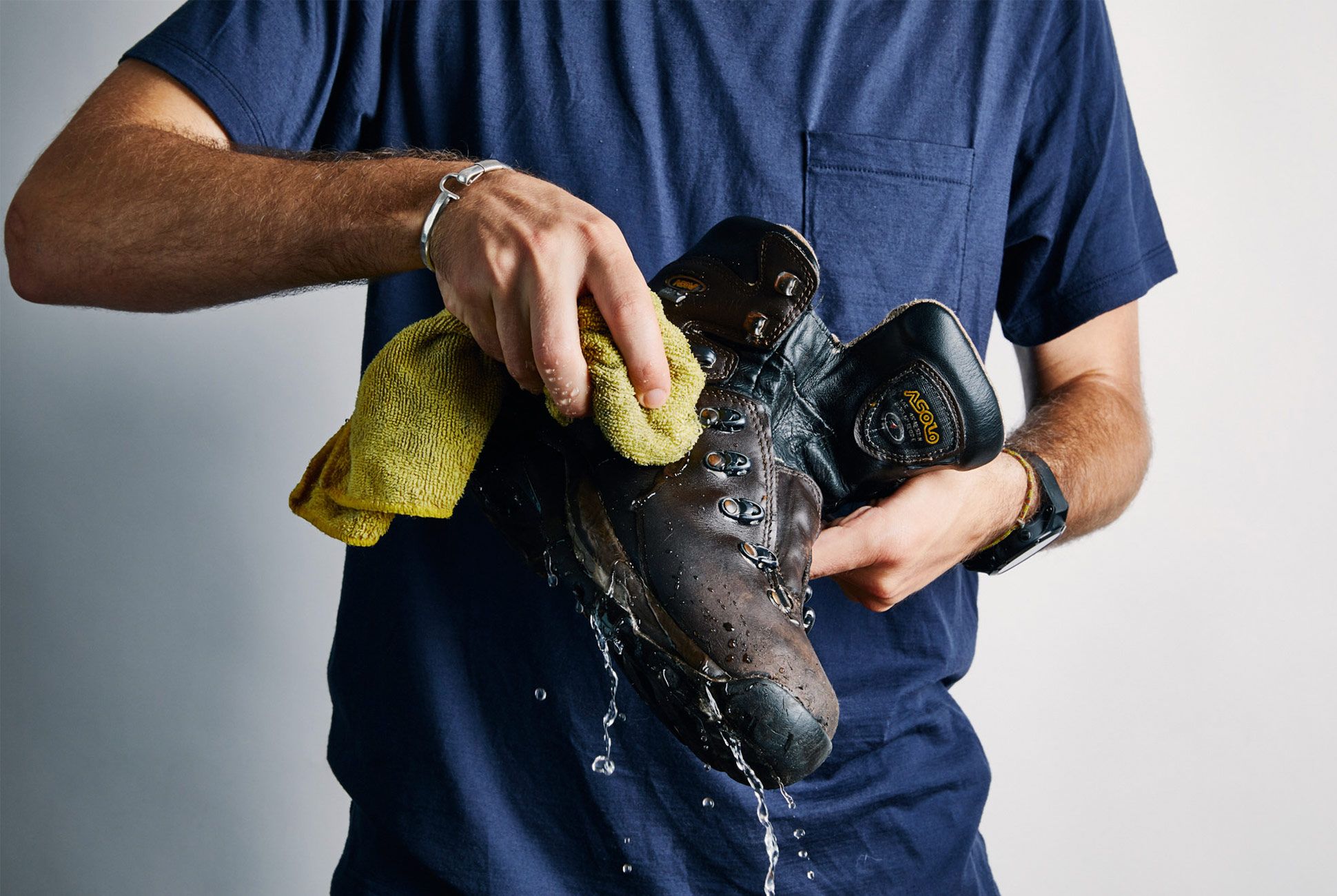 zoomed view of a male cleaning upper of boots using a cloth