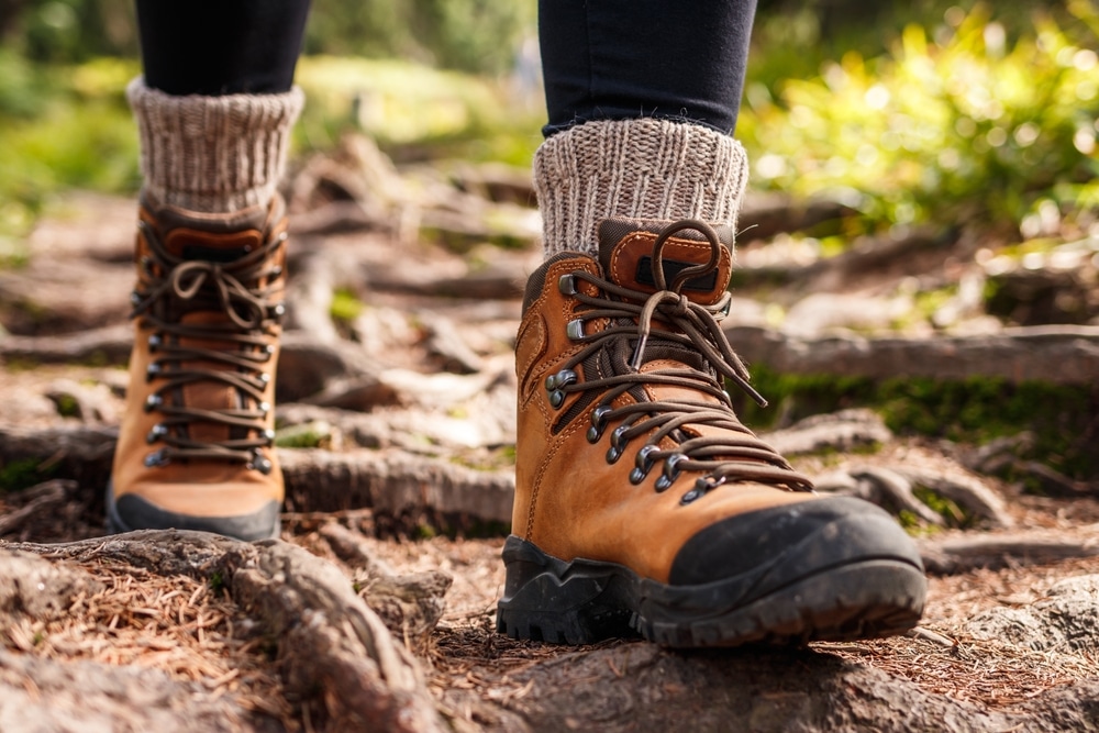 Hiking boot. Legs on mountain trail during trekking in forest. 