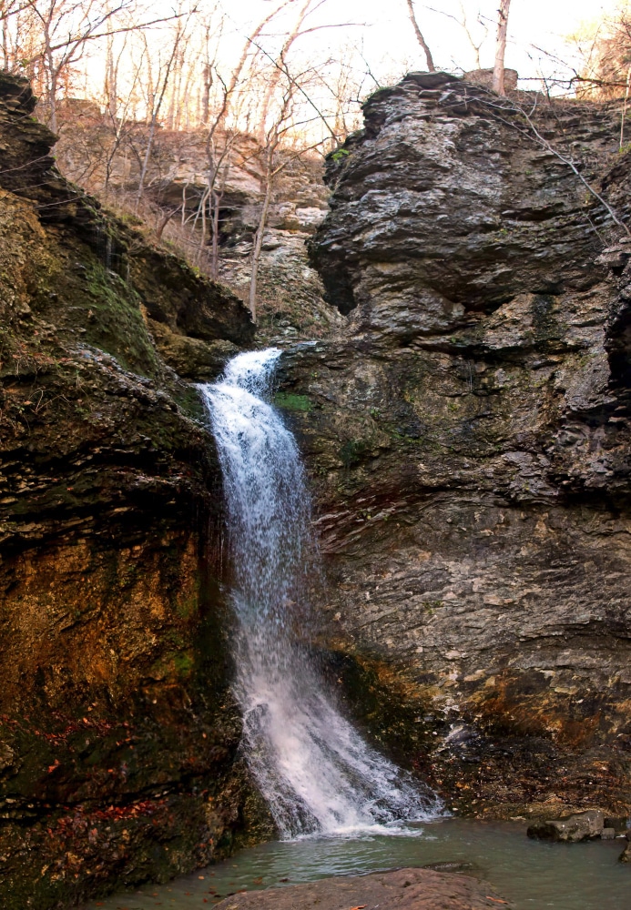 Vertical shot of a powerful waterfall flowing through rocks in a forest 